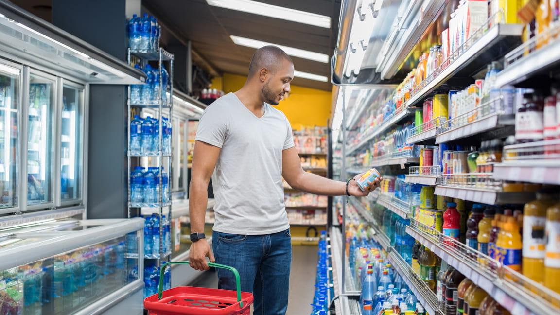 African American man grocery shopping and reading label